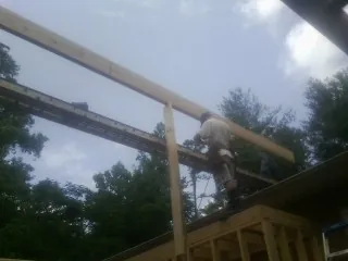 Carpenter setting a ridge beam over a new addition frame — Ice Dam Removal by Roofing Brothers in Saint James City