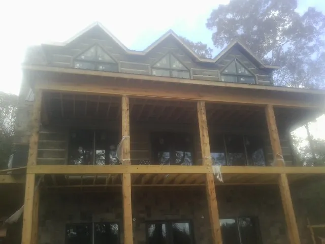 Dormers and porch framing on a large log home under construction — Roof Coating work by our crew in Saint James City