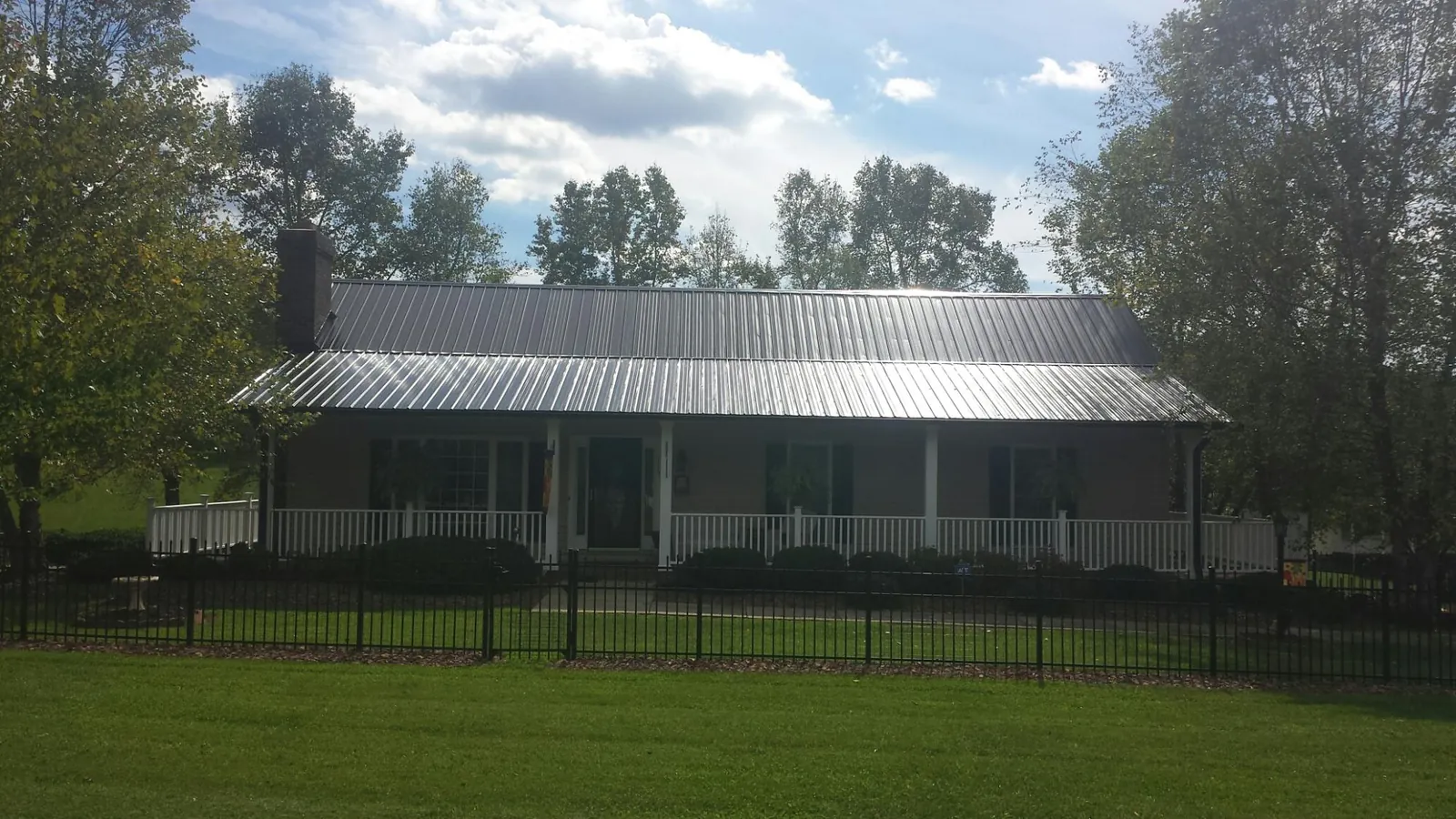 Gray metal roof on a brick ranch with a full width front porch — Gutter Guard Installation work by our crew in Saint James City