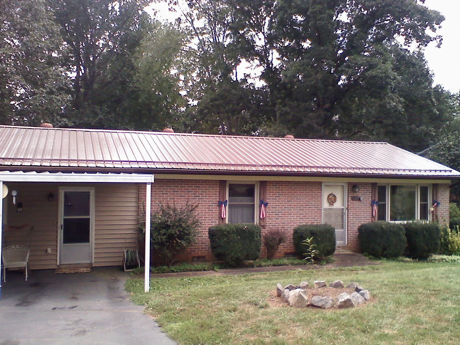 Bronze metal roof and carport on a brick ranch home — Roof Repair work by our crew in Saint James City