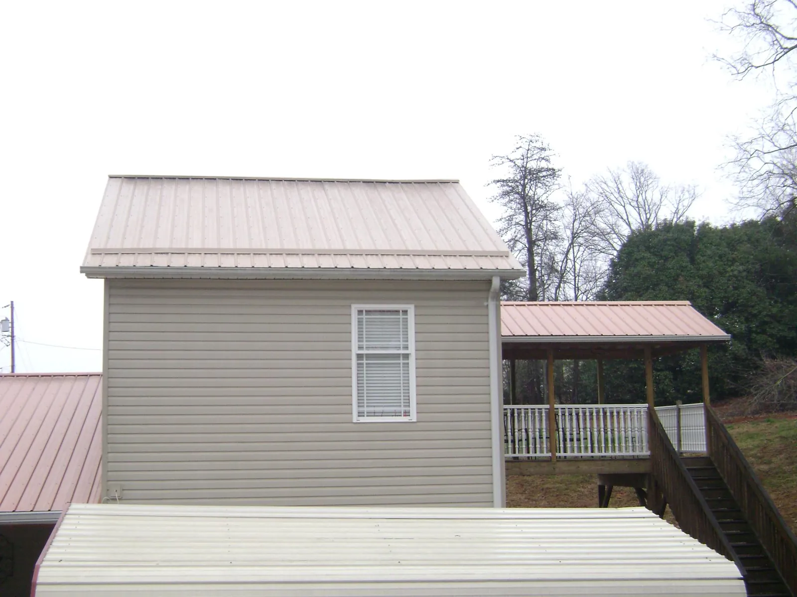 Tan metal roofs on a two story addition and attached porch, from a Roof Replacement job in Saint James City