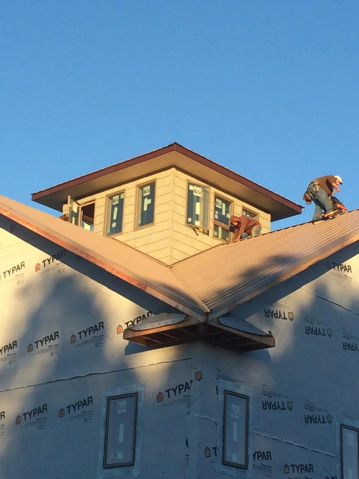 Roofers working around a rooftop cupola on a new metal roof at sunset — Roof Waterproofing in Saint James City by Roofing Brothers